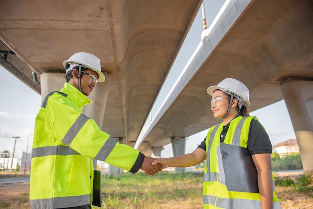 Two engineers discuss about work at the site of large bridge\
under constructionmanagement consulting people discussion with\
engineers about the progress and construction planning of\
highway