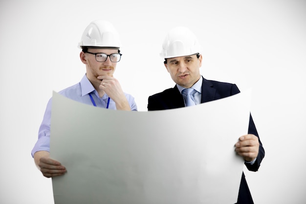 Two engineers in hard hats working, meeting, discussing layout of building