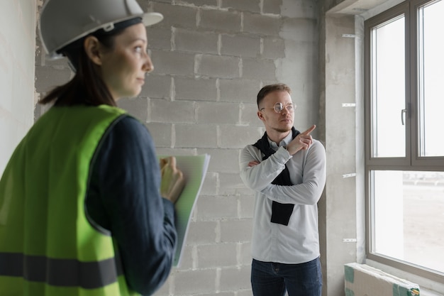 Two engineers a man and a woman in white helmets and green protective vests