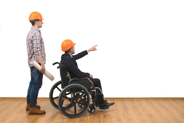 The two engineers with a wheelchair gesture on the white wall background