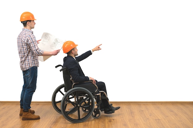 The two engineers with a wheelchair gesture on the white wall background