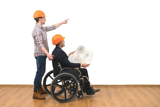The two engineers with a wheelchair gesture on the white wall background