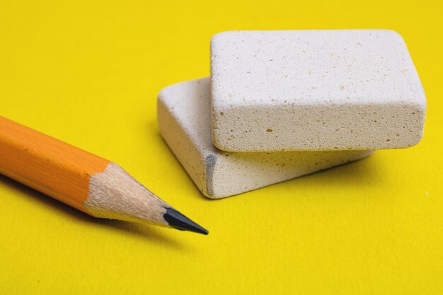 Two erasers and pencil on yellow background