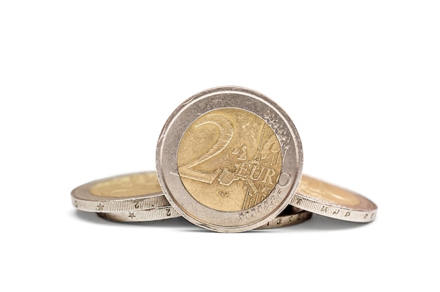 Two euro coin with heap of euro coins on white background