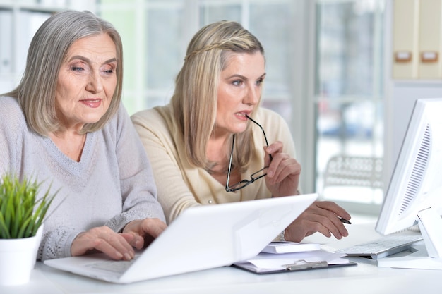 Two excited mature women working in office