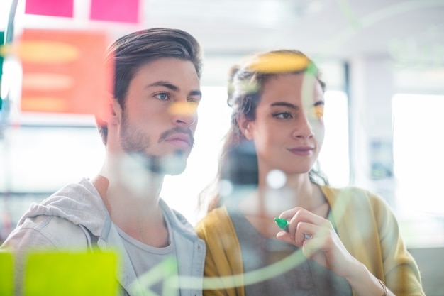 Two executives reading sticky notes on glass wall