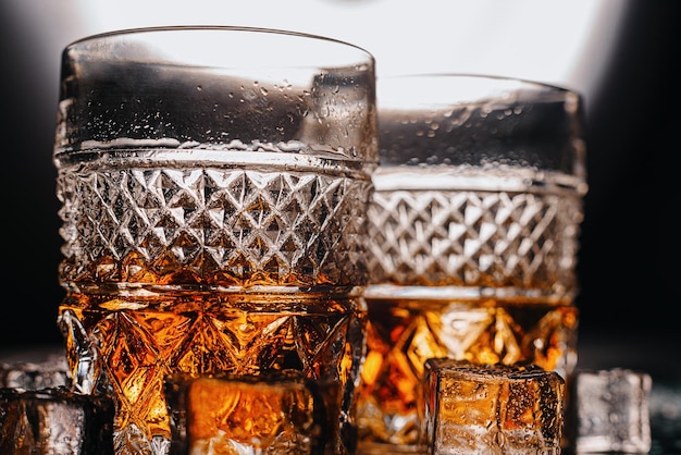 Two expensive glasses of whiskey with ice on a black stone tray