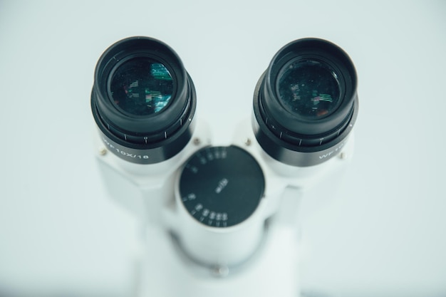 Two eyepieces of the professional microscope in sterile laboratory on white background