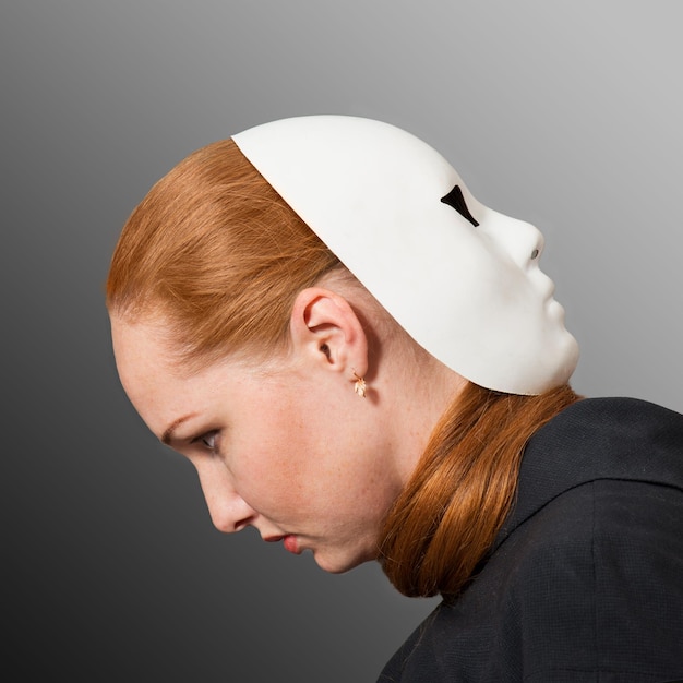 Photo two faces red head woman with white mask worn on the back of her head