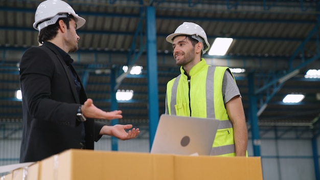 Two factory workers working and discussing manufacturing plan in the factory . Industry and engineering concept .