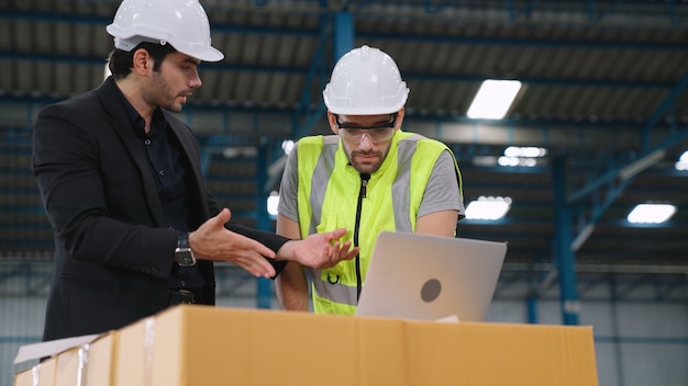 Two factory workers working and discussing manufacturing plan in the factory . Industry and engineering concept .