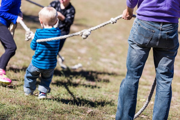 Photo two families playing vintage rope pulling game in the park.