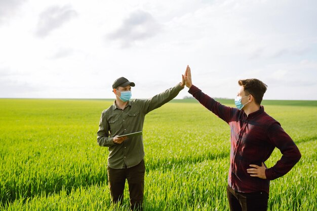 Two farmers in protection mask with tablet in the field modern agriculture technologysmart farming