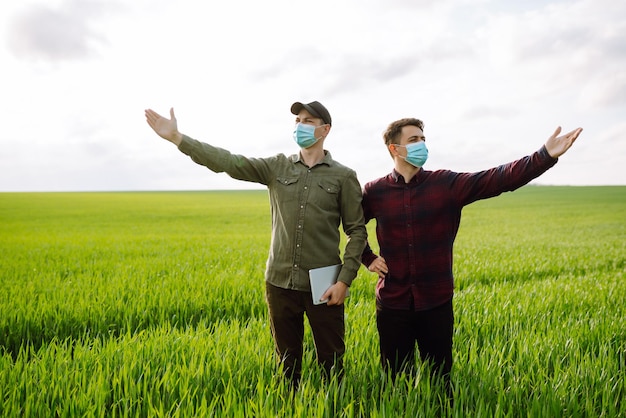 Two Farmers in protection mask with tablet in the field Modern agriculture technologySmart farming