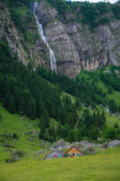 Two farmhouses between mountains in the background a waterfall