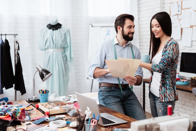 Two fashion designers looking at drawing talking.