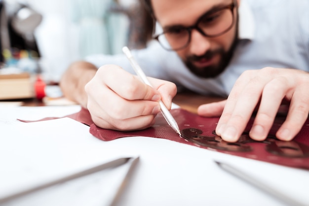 Two fashion designers making cutout on leather