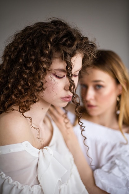 Due modelli femminili di moda su sfondo grigio ritratto in studio due giovani ragazze alla moda in posa