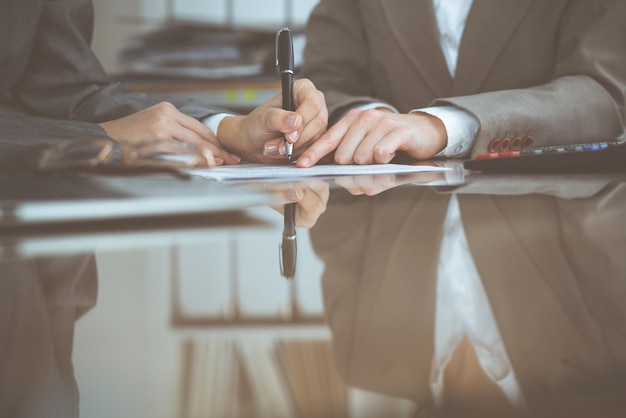 Two female accountants checking financial statement or counting\
by calculator income for tax form, hands close-up. internal revenue\
service inspector checking financial document. planning budget and\
a