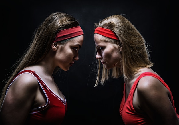 Two female boxers in red sportswear standing face to face. Fighting sport and martial art concept