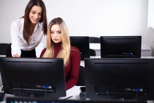 Две коллеги-женщины в офисе работают вместе
