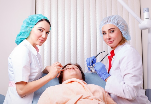 Two female doctors examining patient after plastic surgery