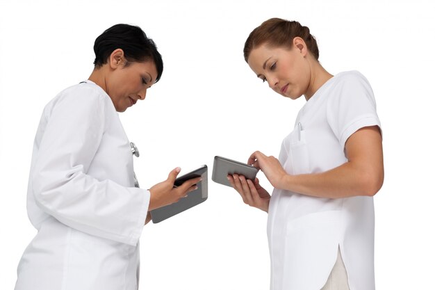 Two female doctors using digital tablets over white background