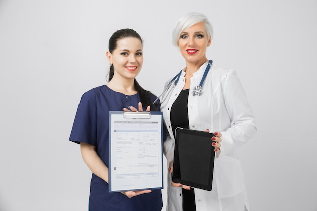 Two female doctors with tablet and sheet with analysis in hands isolated