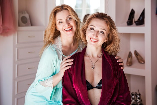 Two female friends in dressing gowns posing in front of the camera.  