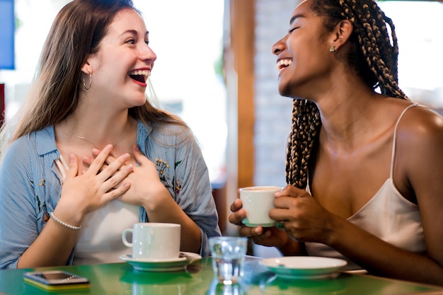 コーヒーショップでコーヒーを飲みながら一緒に時間を楽しんでいる2人の女性の友人。友達のコンセプト。