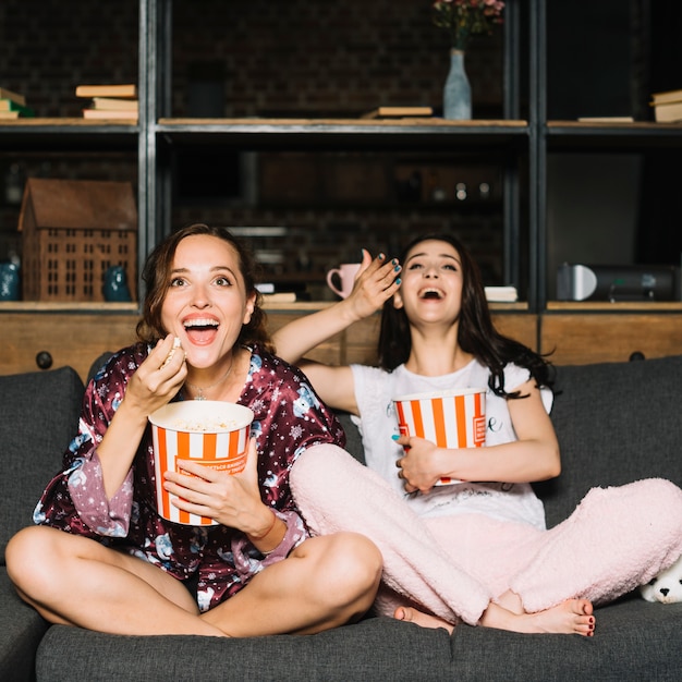 Two female friends laughing while watching comedy movie