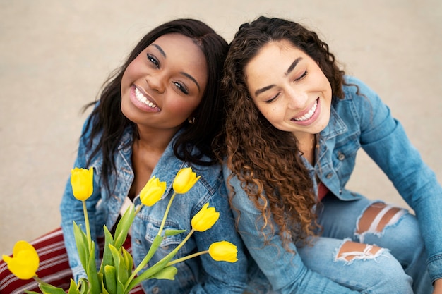 Photo two female friends posing with tulips while out in the city