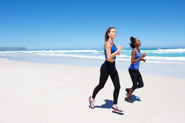 Two female friends running on beach