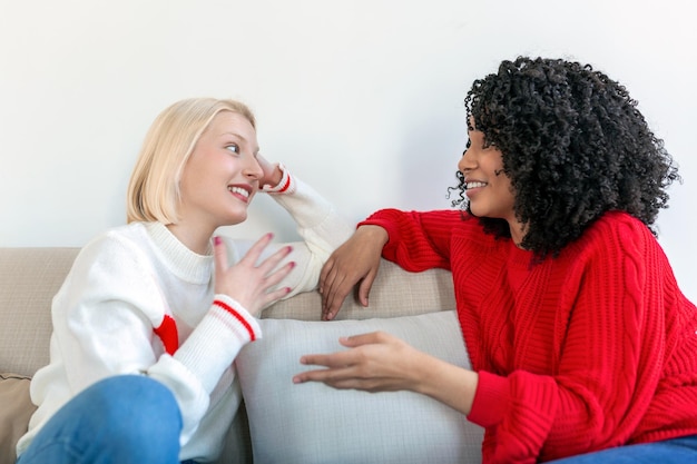 Two female friends sitting on sofa Best friends having coffee together on sofa at home