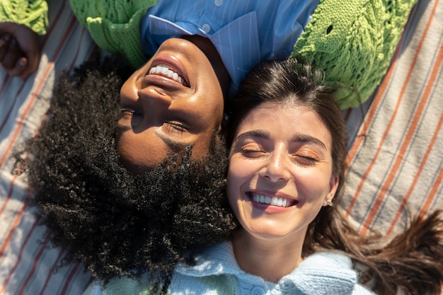 Two female friends smiling with their eyes closed in an outdoor field