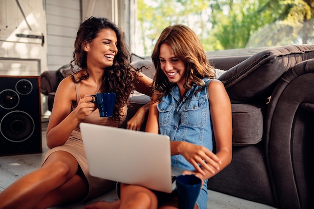 Two female friends using laptop indoors