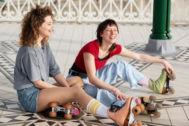 Due amiche con pattini a rotelle che ridono all'aperto