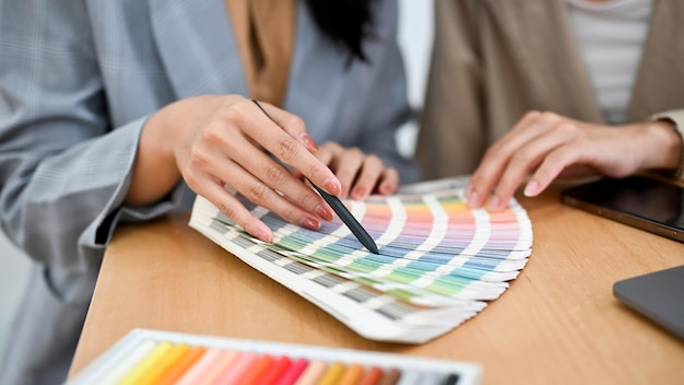 두 명의 여성 그래픽 디자이너가 색상 견본 팔레트의 색상을 검토하고 있습니다.