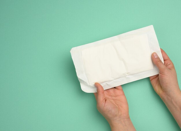 Photo two female hands hold white paper packaging with sterile medical gloves