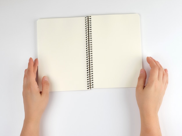 Two female hands holding open notepad with clean sheets 