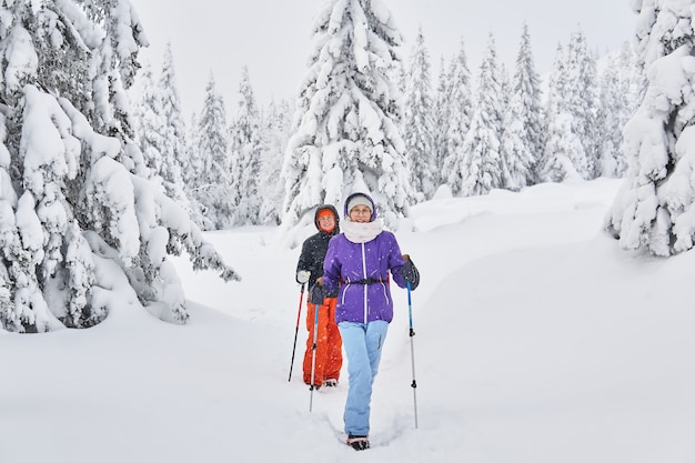 冬の山の雪に覆われた森の2人の女性ハイカー