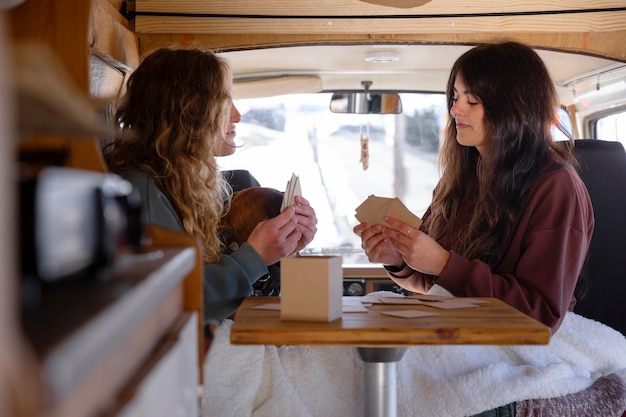 Foto due amanti femminili che giocano a carte durante il viaggio invernale