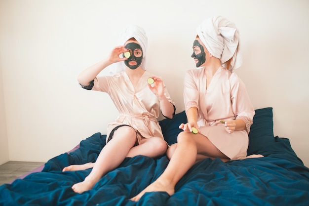 Foto due modelli femminili fanno la maschera per il viso e usano il cetriolo verde fresco