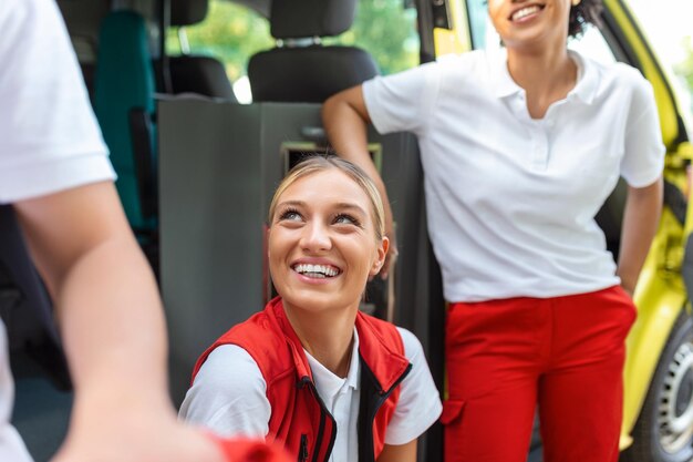 Foto due infermiere vicino ai paramedici dell'ambulanza vicino all'ambulanza sorridenti