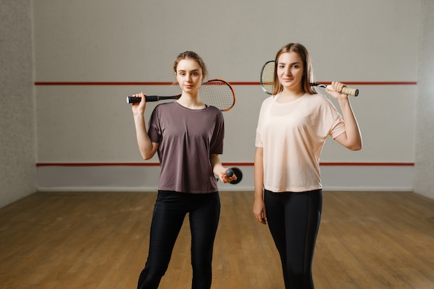 Two female players shows squash rackets