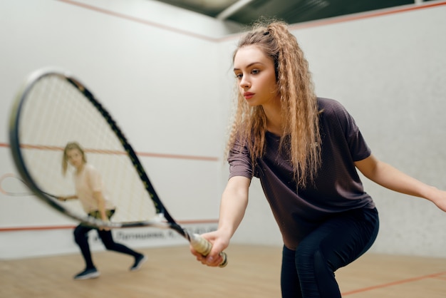 Due giocatrici con racchetta da squash che giocano in campo. ragazza sull'addestramento al gioco, hobby sportivo attivo, allenamento fitness per uno stile di vita sano