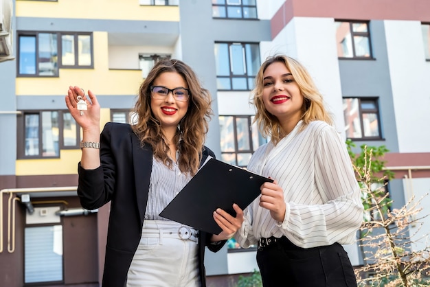 Two female realtor standing outside near new house prepare to sale or rent