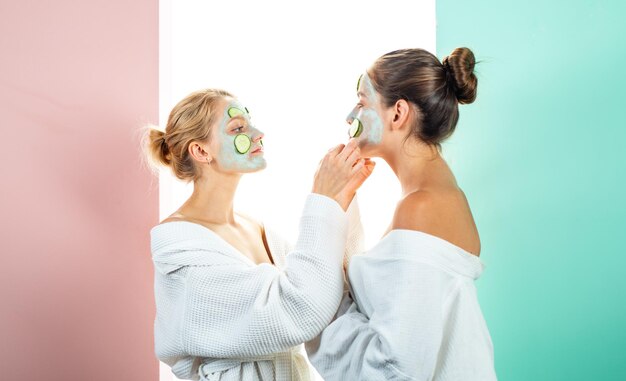 Two female sisters have weekend at bedroom conception of skin care by using fresh cucumber rings and...