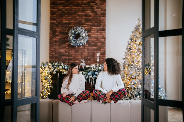 two female student friends sitting on the couch at home