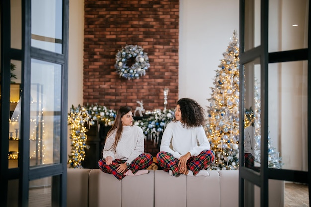 Two female student friends sitting on the couch at home